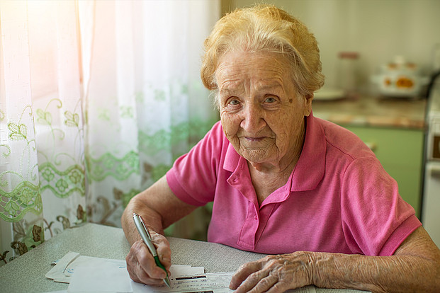 Eine ältere Frau macht die Rechnung für Nebenkosten